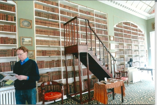 Wim Gohres uit Heemstede op bezoek in Stourhead, mei 2013. 'The Library was completed for Sir Richard Colt Hoare in 1802 to contain his books on English history and typography. The splendid furniture was specially made for the room in 1804-05 by the younger Chippendale, including the library steps, the chairs and the large pedestal desk on which stands Rysbrack's model for his statue of Hercules in the Pantheon. The lunettes formed at each end of the room by the barrel vault are painted with copies of Raphael frescoes in the Vatican by Samuel Woodforde and Francis Eginton (on glass.'